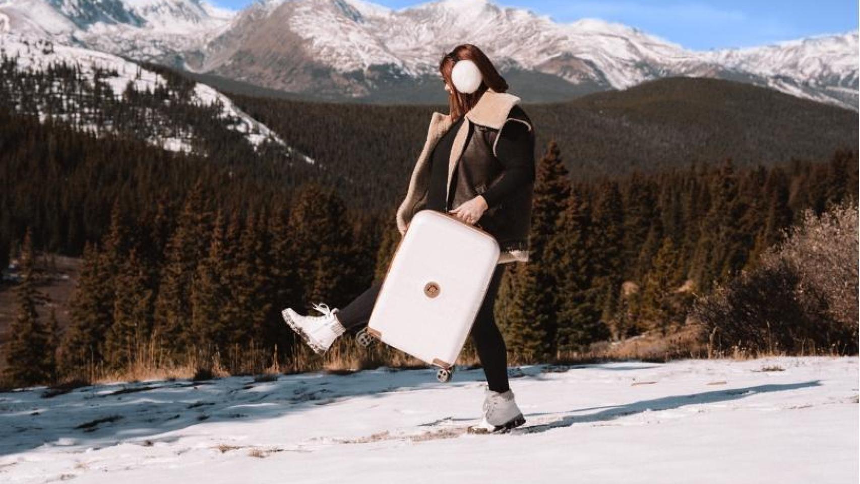 Una chica con una maleta Delsey Paris en la nieve.
