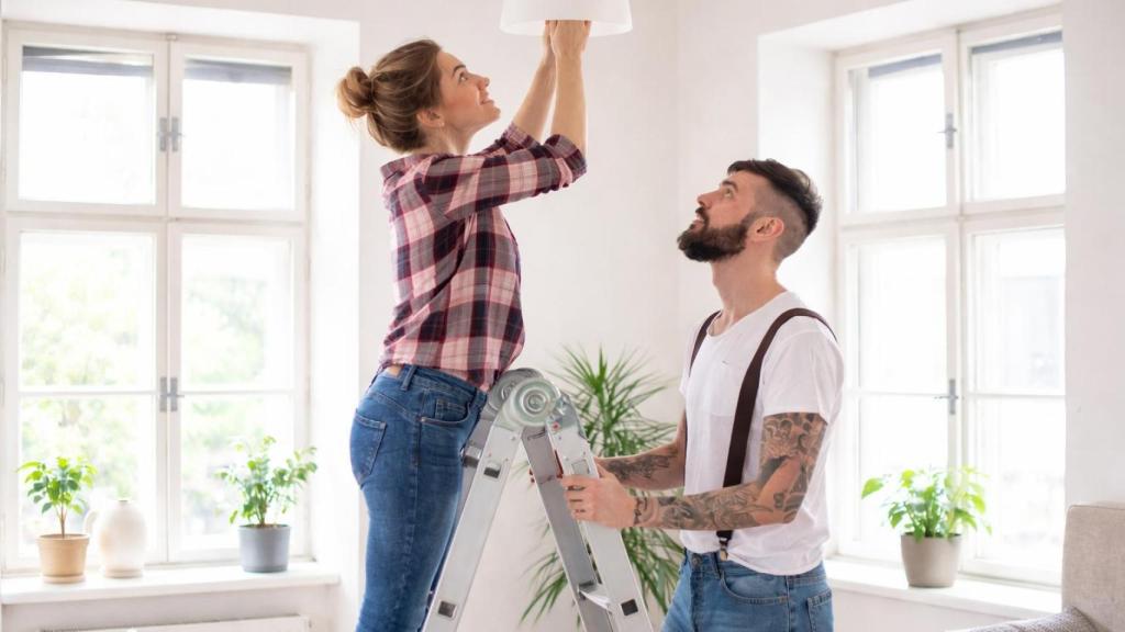 Una pareja joven colocando una bombilla.