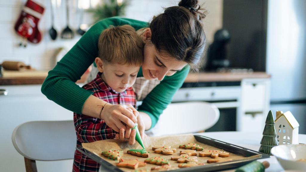 Una madre con su hijo preparando galletas navideñas.