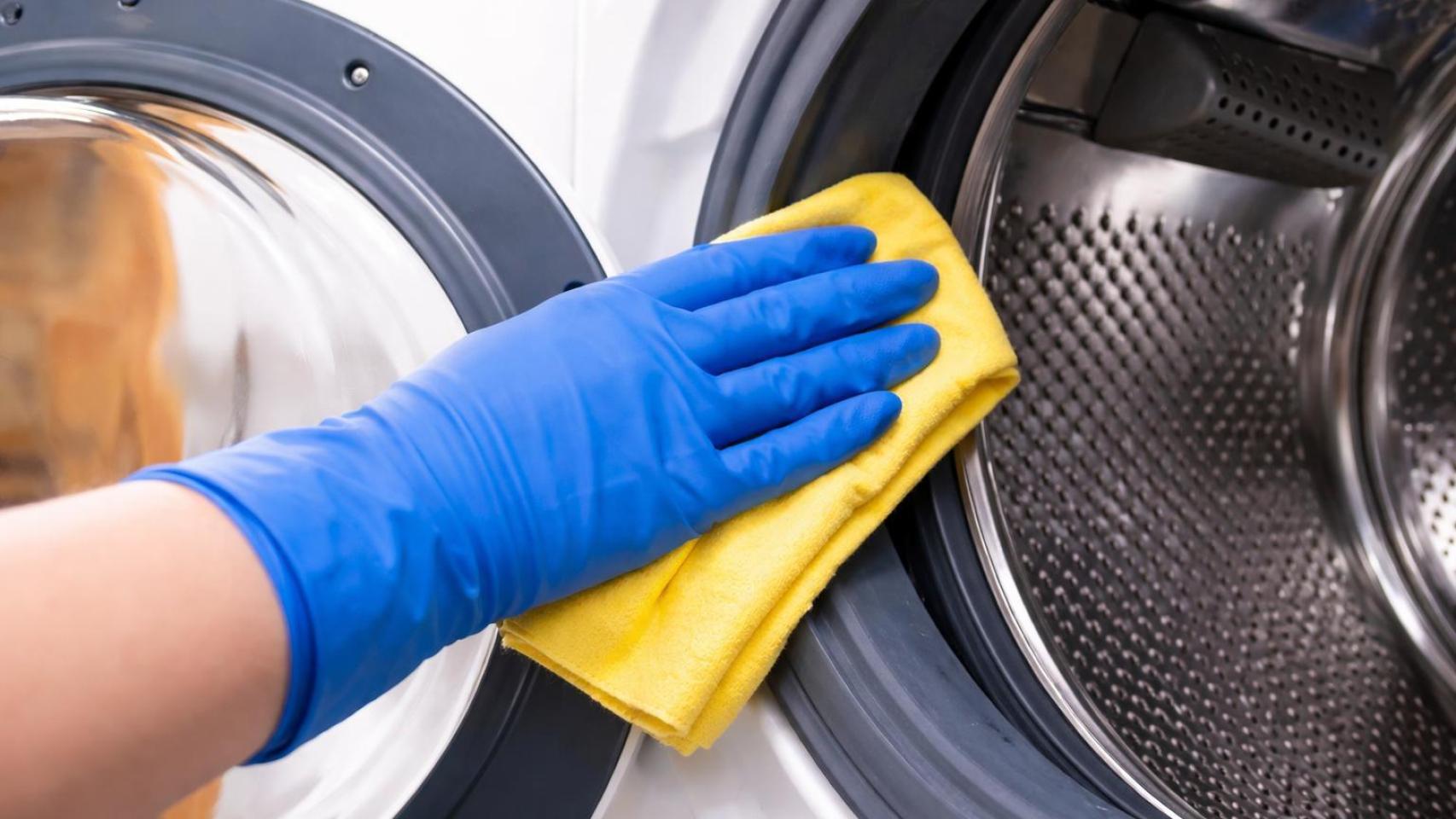 Una persona limpiando la lavadora.