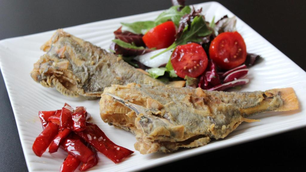 Un plato de peces reloj fritos con ensalada y pimientos rojos.