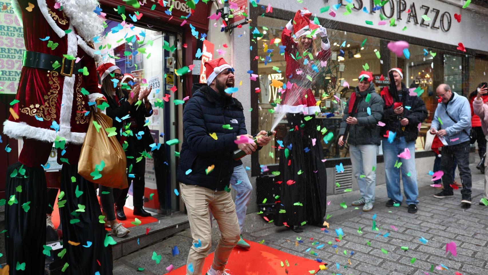 Varias personas celebran a las puertas de una administración de lotería este lunes en Toledo, donde se ha vendido el número 78.477, que ha sido agraciado con un cuarto premio.