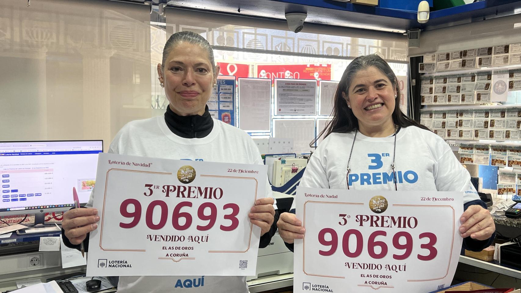 Las dos empleadas de la administración de Os Rosales, con el cartel y las camisetas.