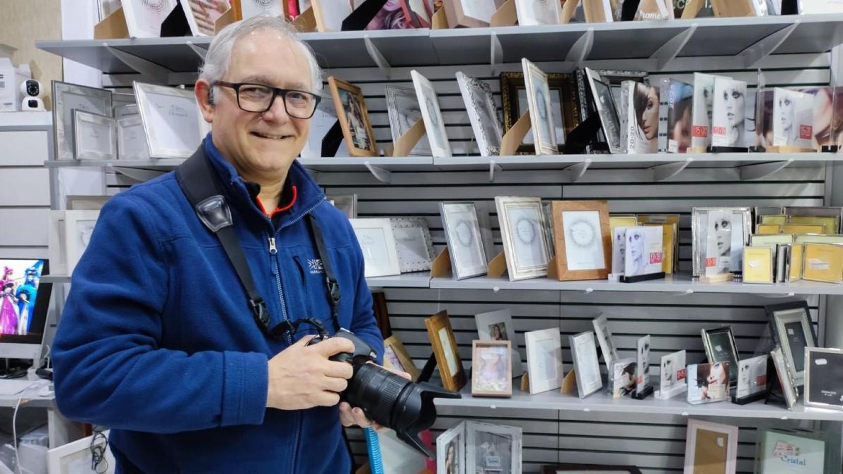 Roberto Cruz, con una cámara y junto a marcos para fotografías en el interior de Foto Cruz.
