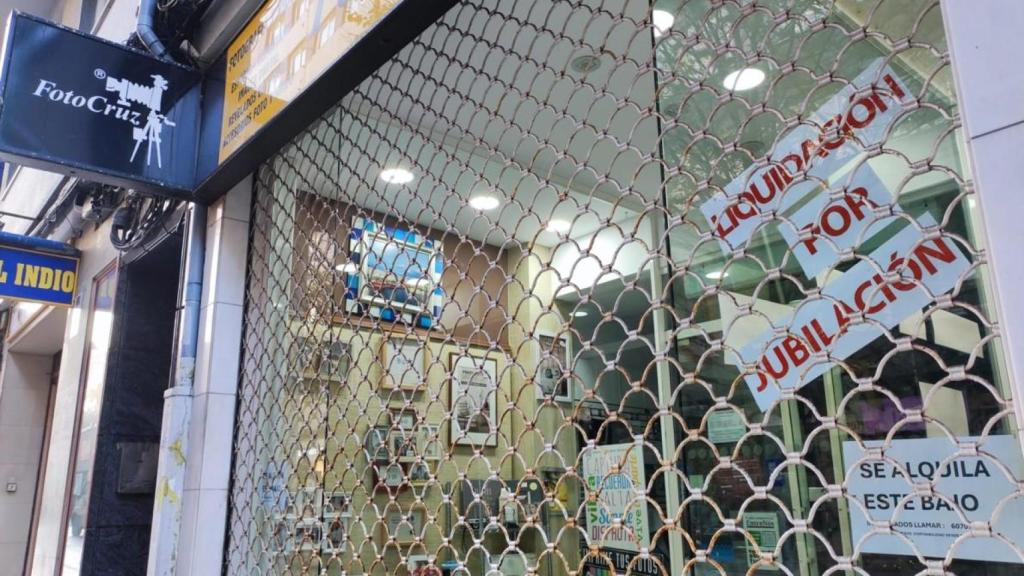 Entrada a Foto Cruz en la calle Barcelona, con el anuncio de liquidación y alquiler de bajo.