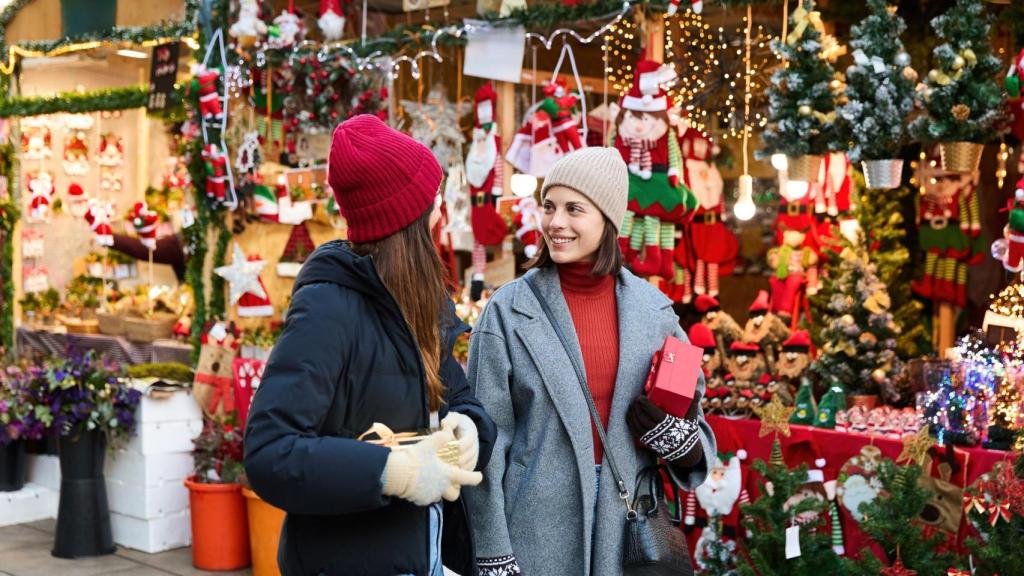 Dos mujeres comprando en un mercadillo navideño.