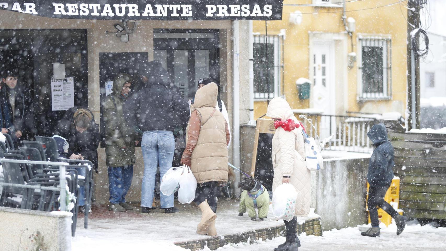 Varias personas entran a un restaurante durante la nevada en Lugo