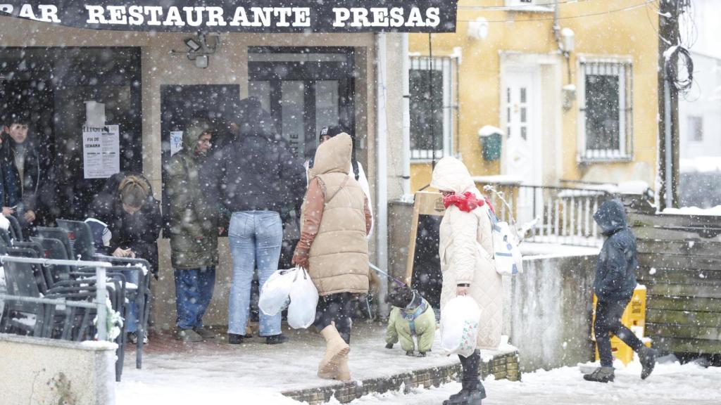 Varias personas entran a un restaurante durante la nevada en Lugo
