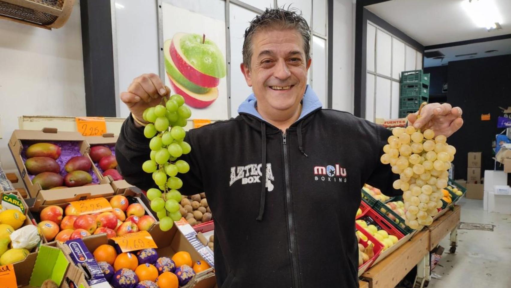 José Barrientos con un ramo de uvas de Perú y otro de uvas aledo en la frutería A Laranxa de A Coruña.