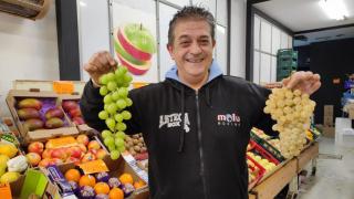 José Barrientos con un ramo de uvas de Perú y otro de uvas aledo en la frutería A Laranxa de A Coruña.