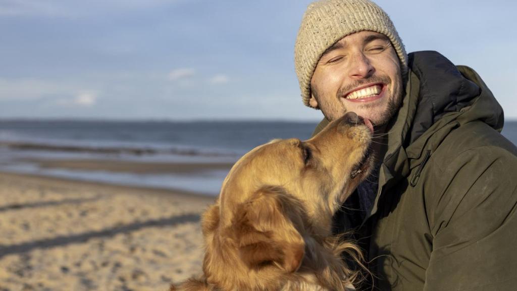 Un hombre con un perro en la playa.