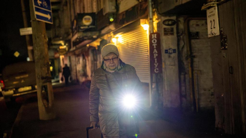 Uma mulher caminha com uma lanterna pelas ruas de Kiev, na escuridão total.