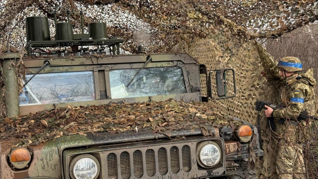 Um soldado ucraniano esconde um Hummer nos arredores de Kupyansk.