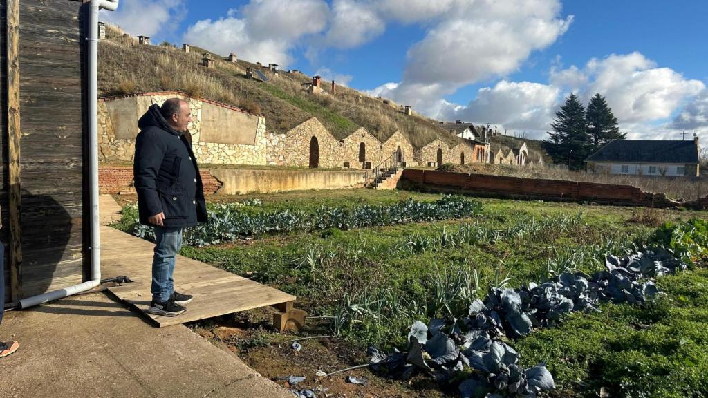 José Gordón frente a su huerto y las bodegas excavadas donde almacenan vino, cecina y otros productos de la finca.