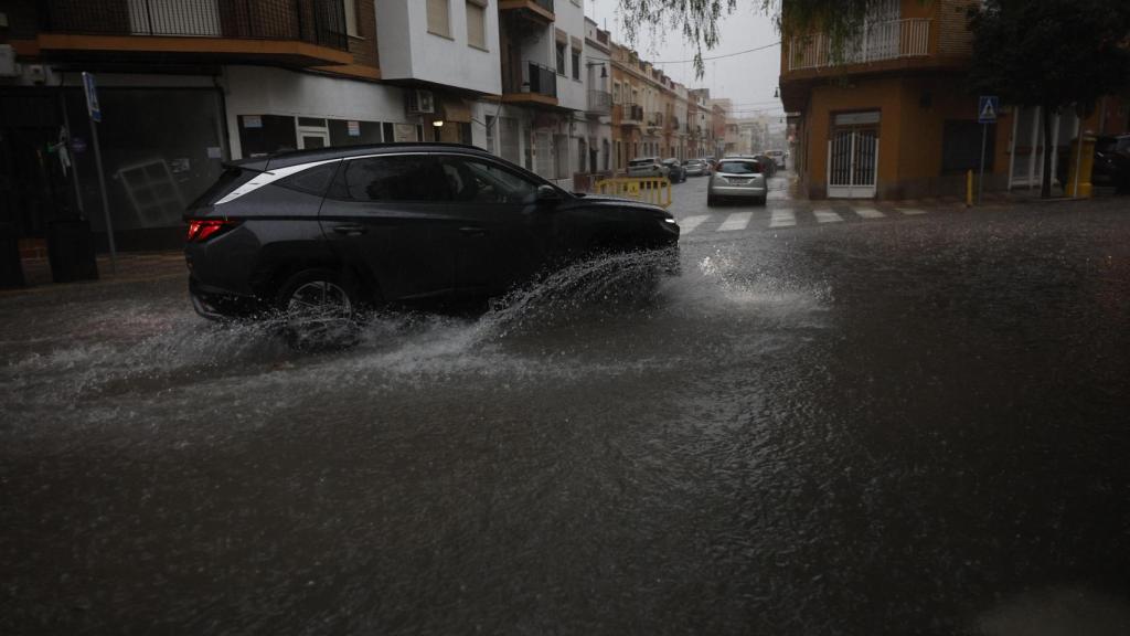n vehículo transita por una calle anegada en la localidad de l'Alcúdia (Valencia) este domingo.