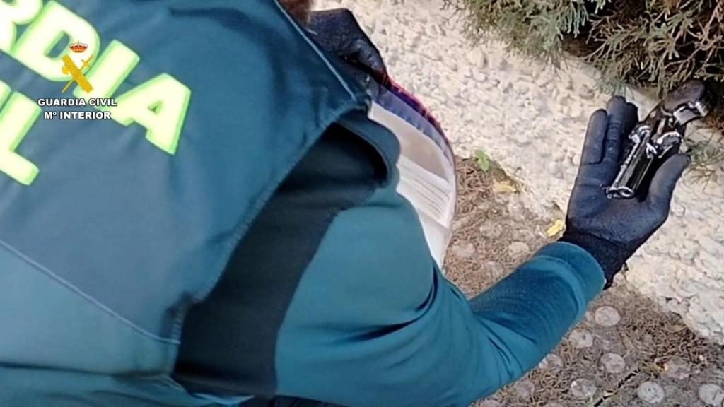 Un agente muestra el arma de fuego usada por los atracadores.