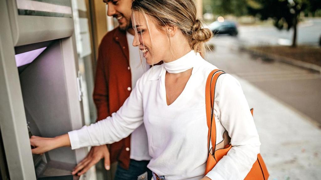 Una pareja sacando dinero de un cajero.