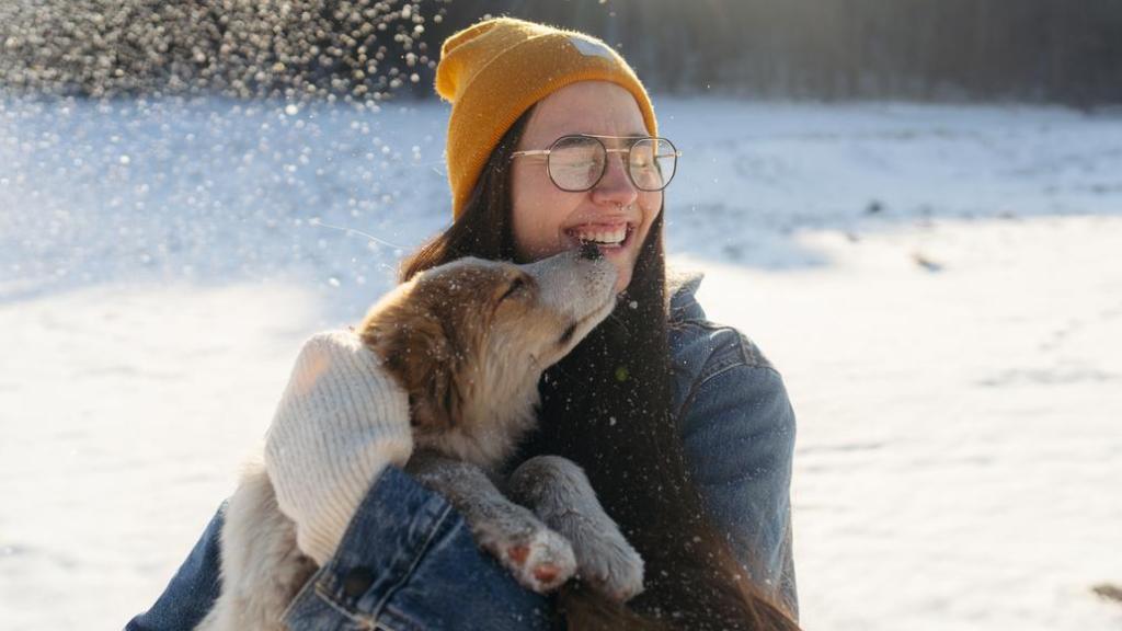 Una chica con un perro en brazos en la nieve.