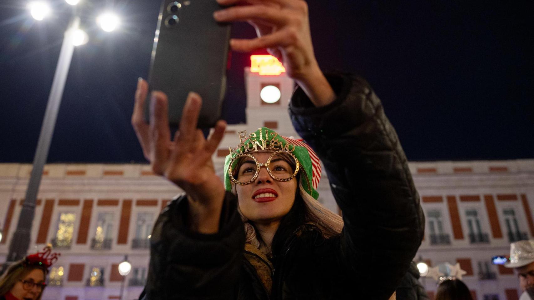 Una mujer sostiene un teléfono durante la celebración de las Campanadas de Año Nuevo de 2026 en Madrid.