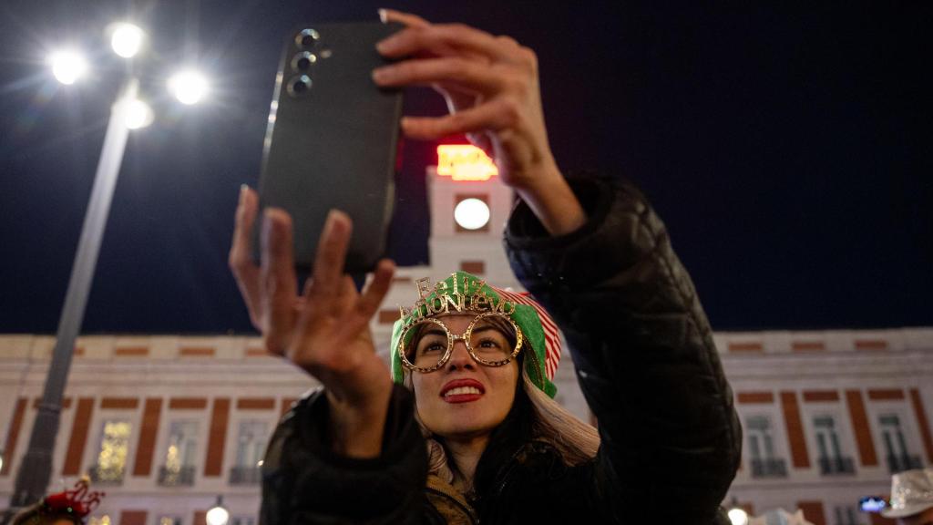 Una mujer sostiene un teléfono durante la celebración de las Campanadas de Año Nuevo de 2026 en Madrid.