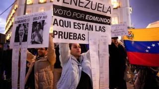 Venezolanos exhiben el retrato de Edmundo González y una copia de las actas de las elecciones, anoche en la Puerta del Sol de Madrid.