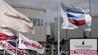 Fotomontaje de un depósito de petrolero de PDVSA, la petrolera estatal de Venezuela, con banderas de las petroleras estadounidenses ExxonMobil, Chevron, ConocoPhillips y Continental Resources.