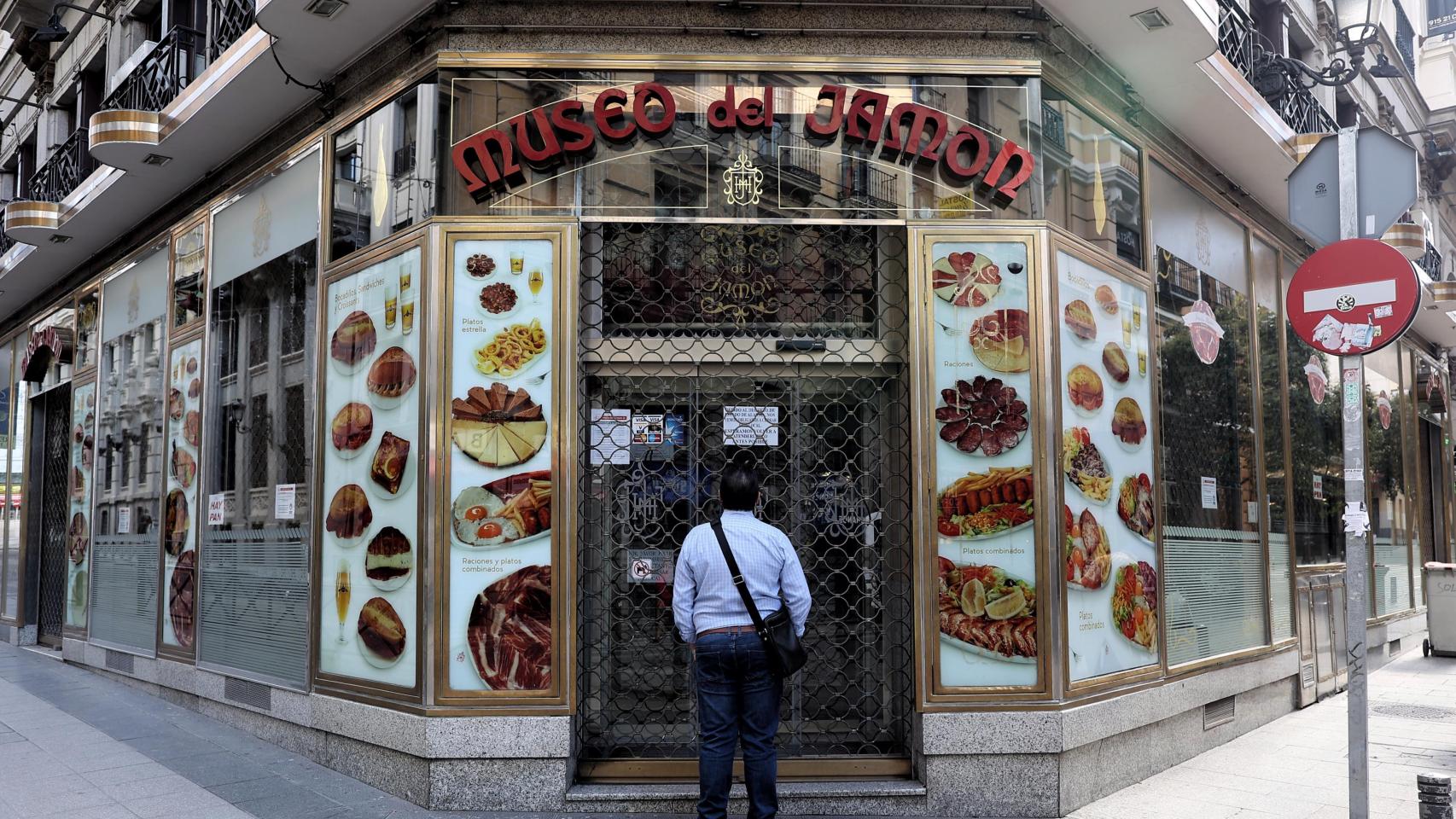 Una persona observa un local del Museo del Jamón desde el exterior.