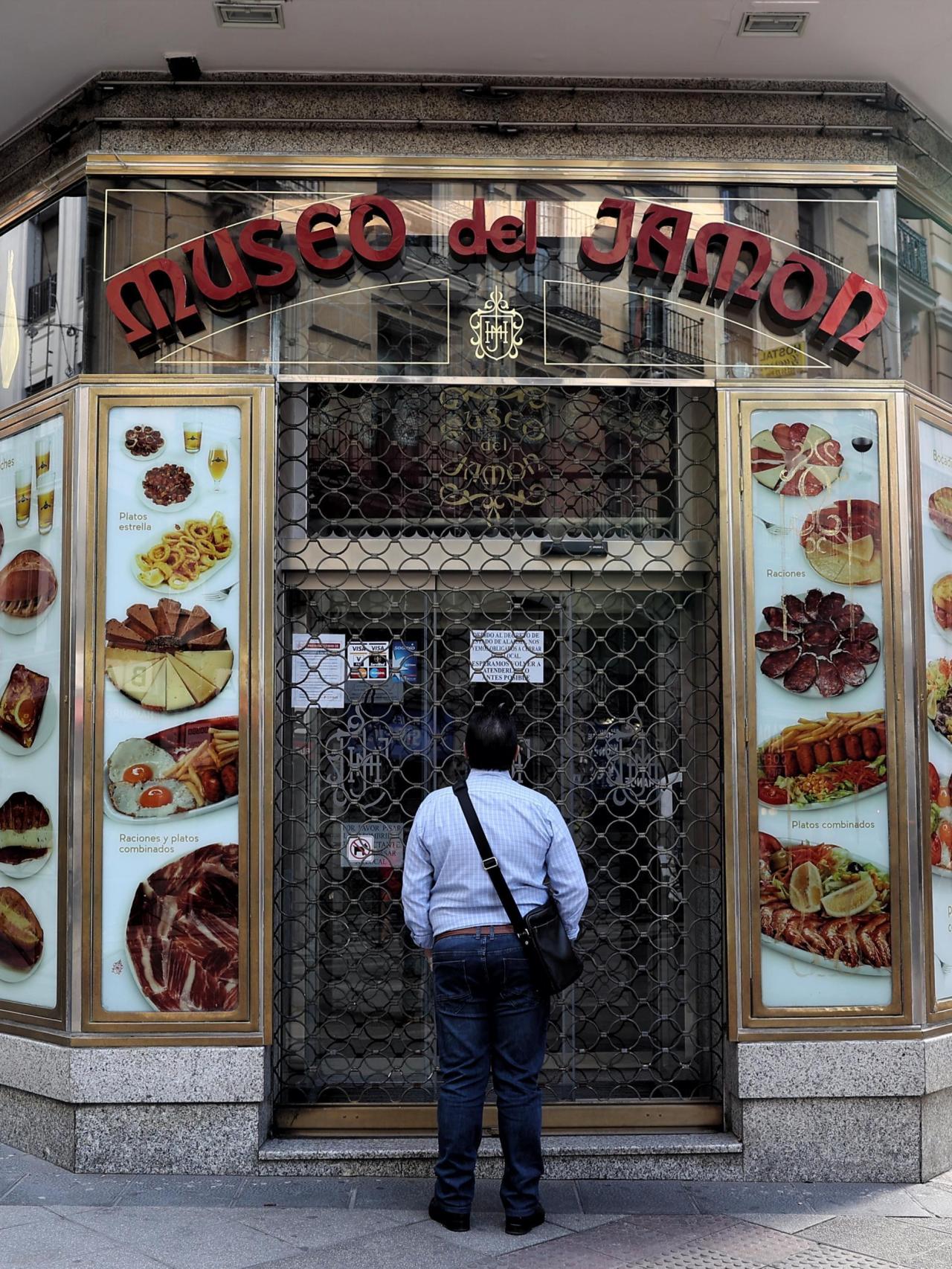 Una persona observa un local del Museo del Jamón desde el exterior.