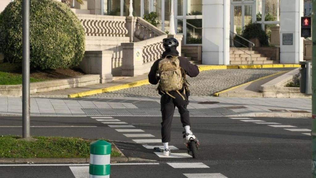 Un usuario de patinete eléctrico espera para cruzar en el Paseo Marítimo de A Coruña.