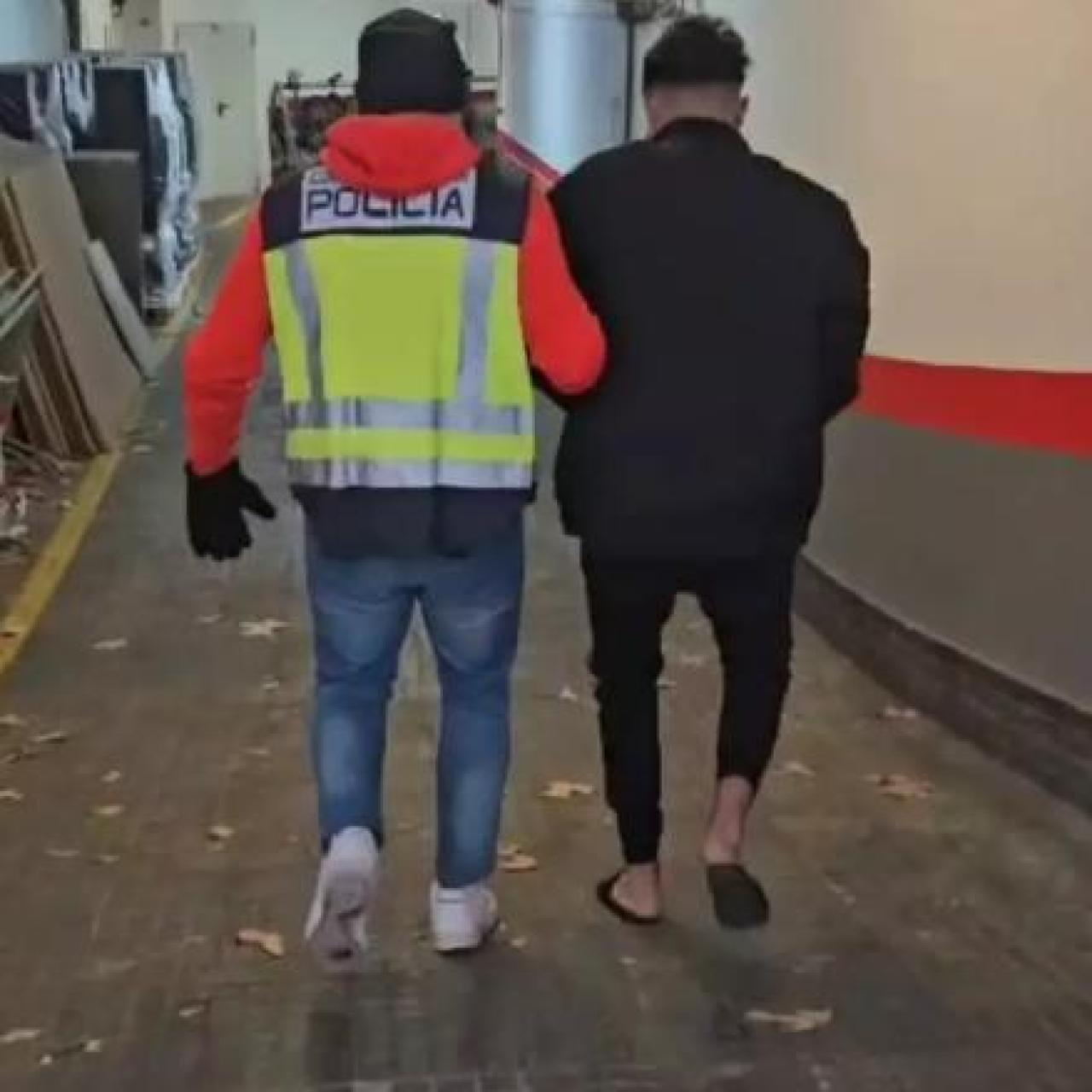 Uno de los detenidos, custodiado por un agente de la Policía Nacional.