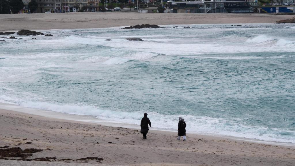Gente paseando por la playa de Riazor con temporal