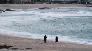 Gente paseando por la plaza de Riazor con temporal