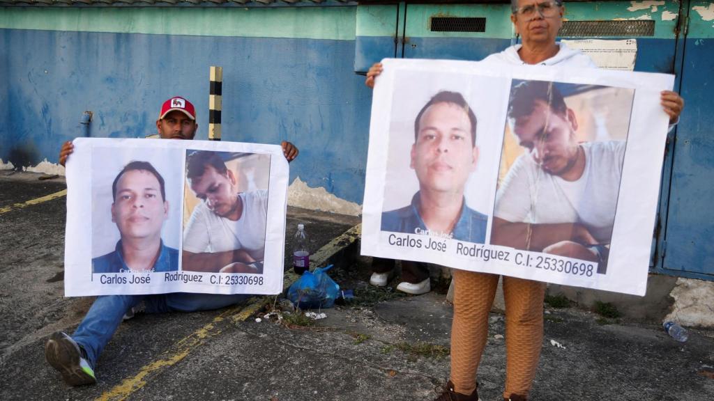 La madre y el hermano de Carlos Rodríguez sostienen carteles con sus fotos, mientras esperan a las puertas del centro de detención de Helicoide.