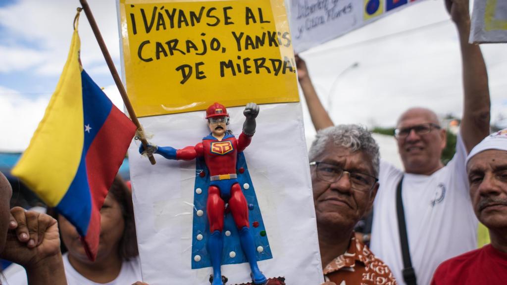 Um homem segura uma placa com um boneco Super Bigote durante manifestação neste sábado em Caracas, na Venezuela.