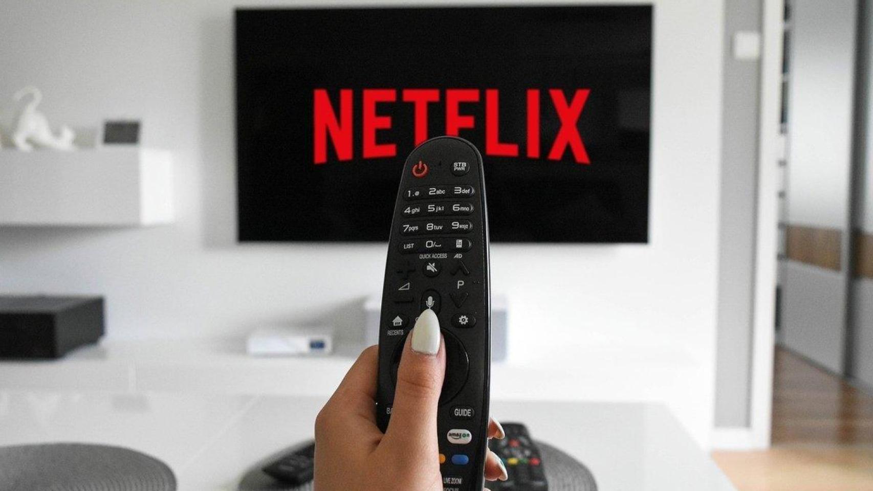 Logo de Netflix en una televisión, con una mujer utilizando un mando a distancia.