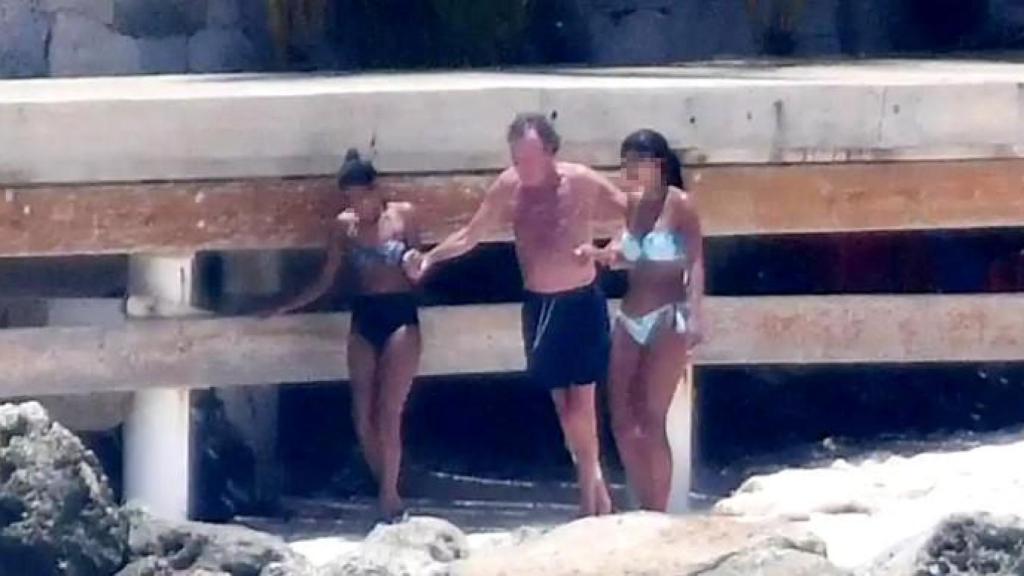 Julio Iglesias, ayudado por dos trabajadores para entrar al mar, en 2020.