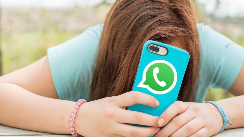 Una adolescente mira un smartphone con el icono de WhatsApp