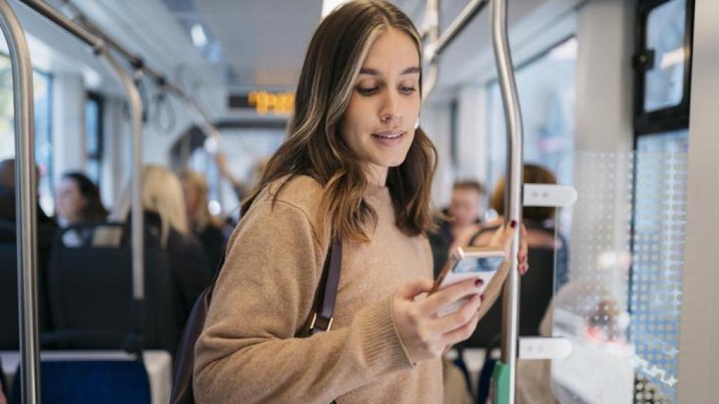 Mujer en el transporte público con el móvil.