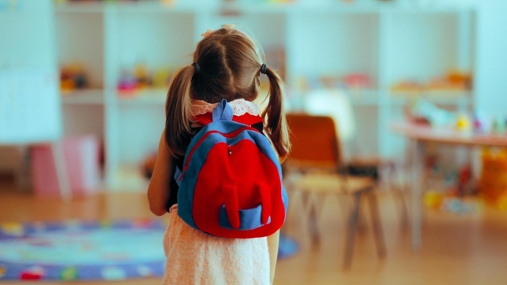 Una niña entra en una clase de un colegio