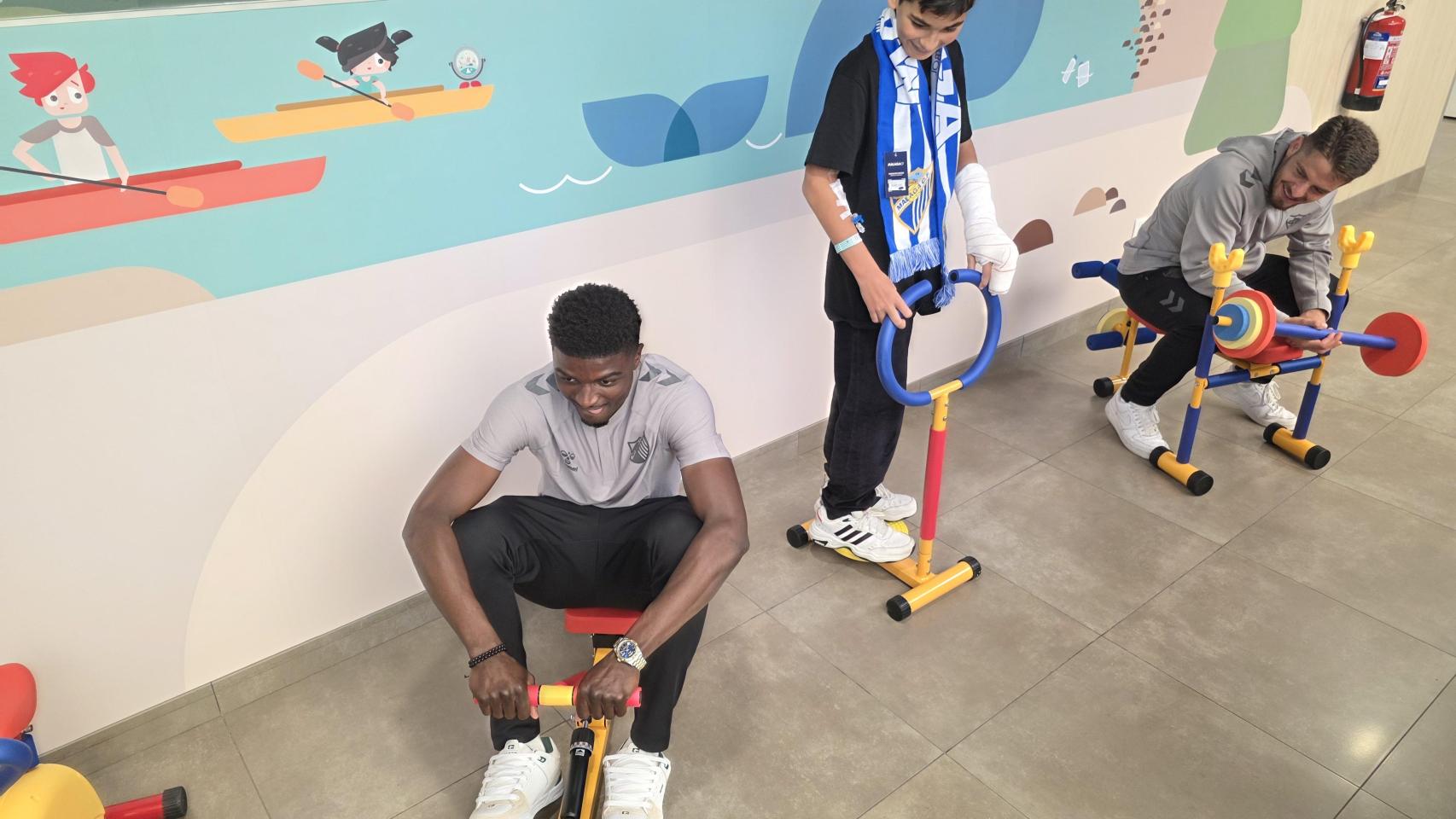 Los jugadores del Málaga CF con un niño en el mini gimnasio del Hospital Quirónsalud Málaga.