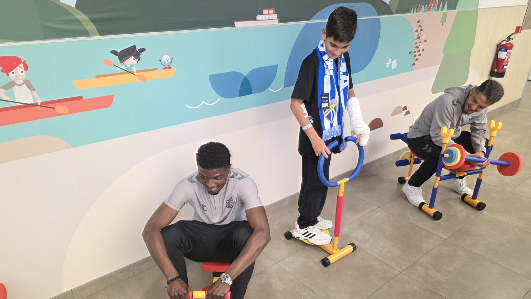 Los jugadores del Málaga CF con un niño en el mini gimnasio del Hospital Quirónsalud Málaga.