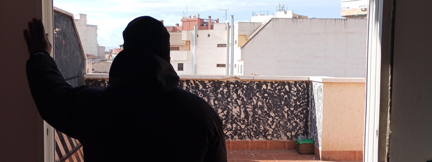 El guineano que ha declarado ante la Guardia Civil, este miércoles, asomado a la terraza del ático desde la que cayó al vacío su amigo 'Momo'.