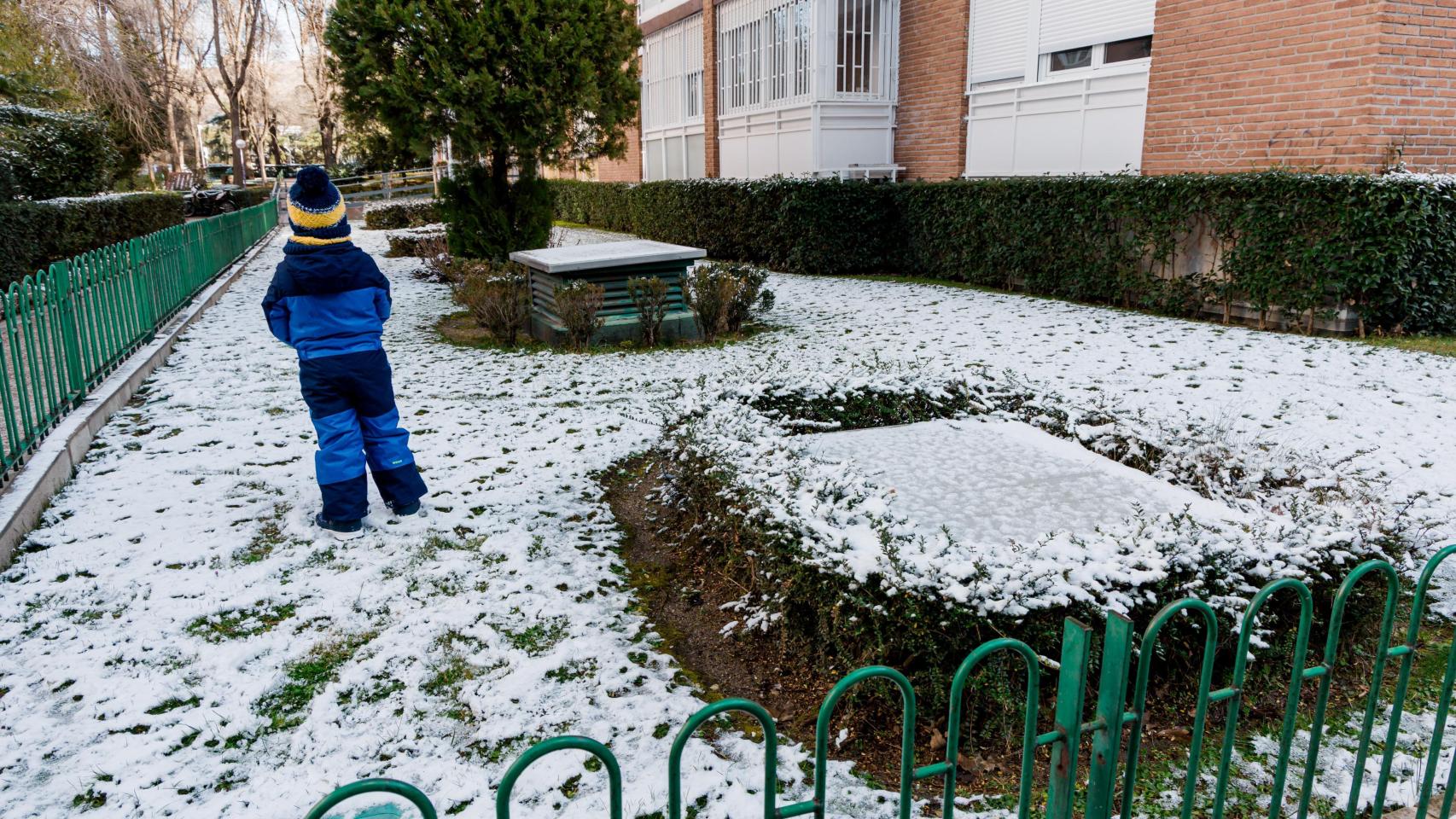 Un niño juega con la nieve en un jardín de Madrid.