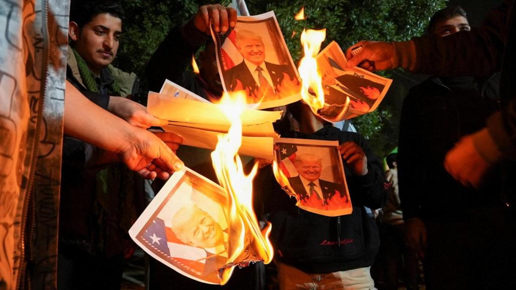 Partidarios de grupos armados chiítas iraquíes queman imágenes del presidente estadounidense Donald Trump y del primer ministro israelí Benjamin Netanyahu, durante una manifestación en solidaridad con el Gobierno de Irán en Teherán, frente al consulado iraní en Basora.