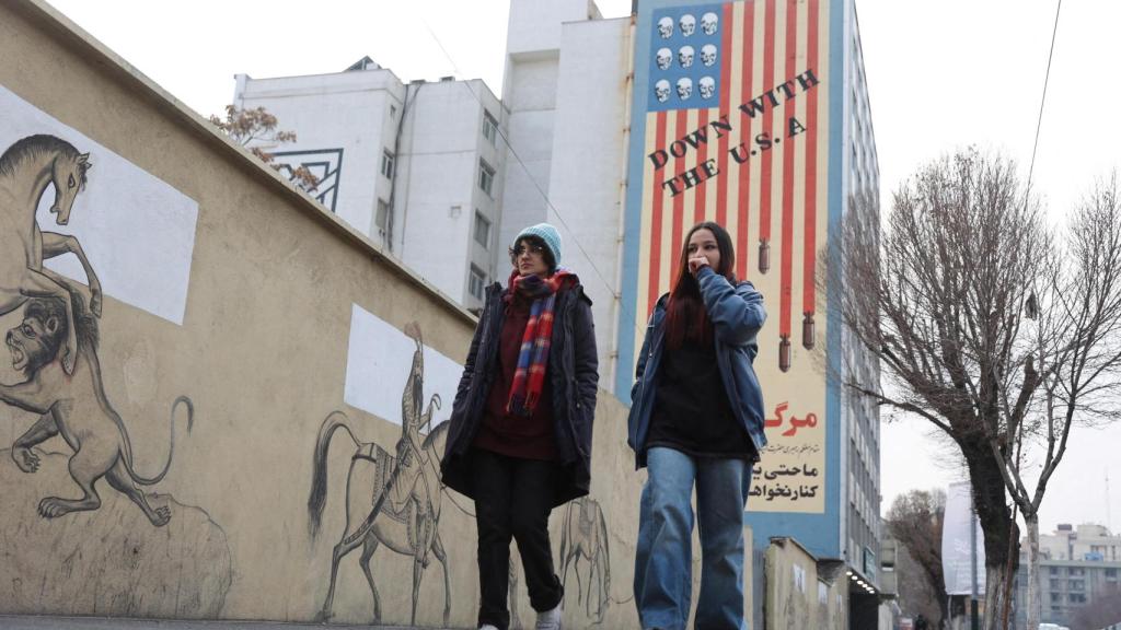 Dos mujeres caminan junto a un mural antiestadounidense en una calle de Teherán.