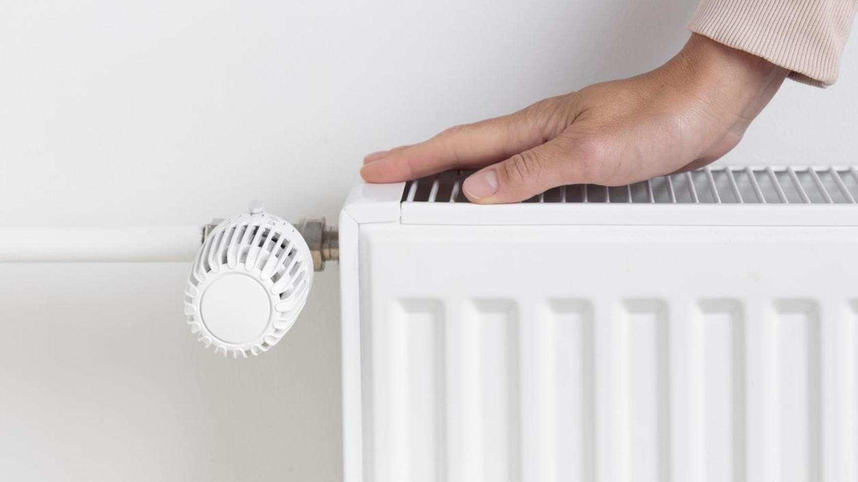 Una mujer con la mano en la calefacción.