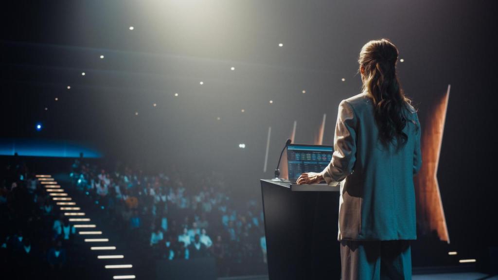 Oradora anónima hablando con la audiencia mientras sube al escenario de la conferencia.