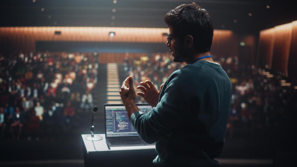 Retrato de un joven orador de pie en el escenario de una conferencia.