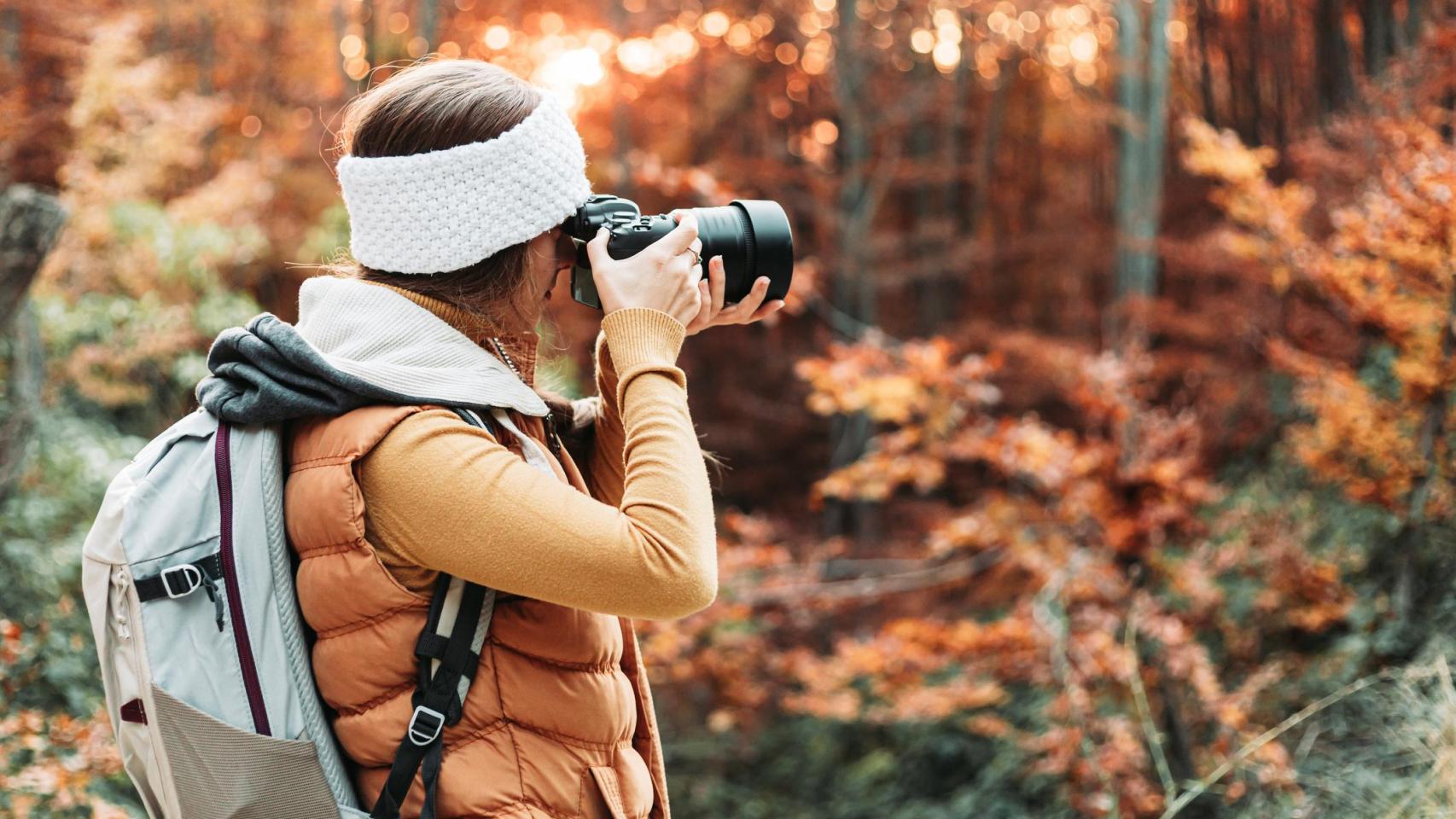 Joven fotógrafa tomando fotos en la naturaleza con su cámara.