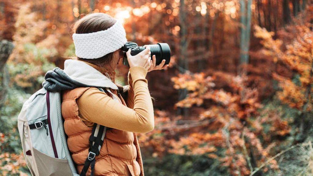 Joven fotógrafa tomando fotos en la naturaleza con su cámara.
